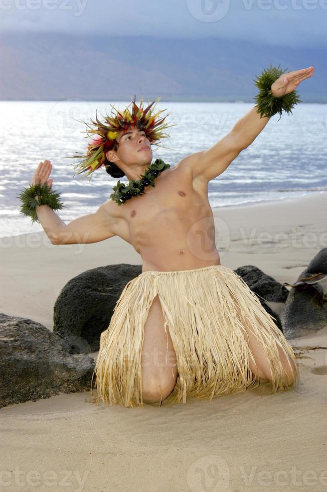 Jeune Masculin hula Danseur a genou retour sur le le sable dans une traditionnel hawaïen hula pose. photo