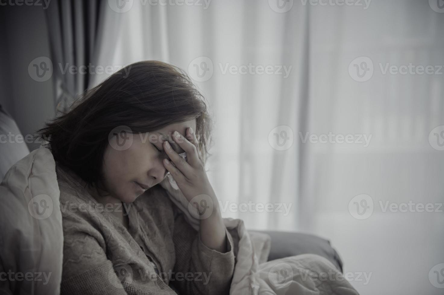 une femme malade asiatique s'assoit sur le canapé reste à la maison, la femme se sentait mal, voulait s'allonger et se reposer, forte fièvre photo