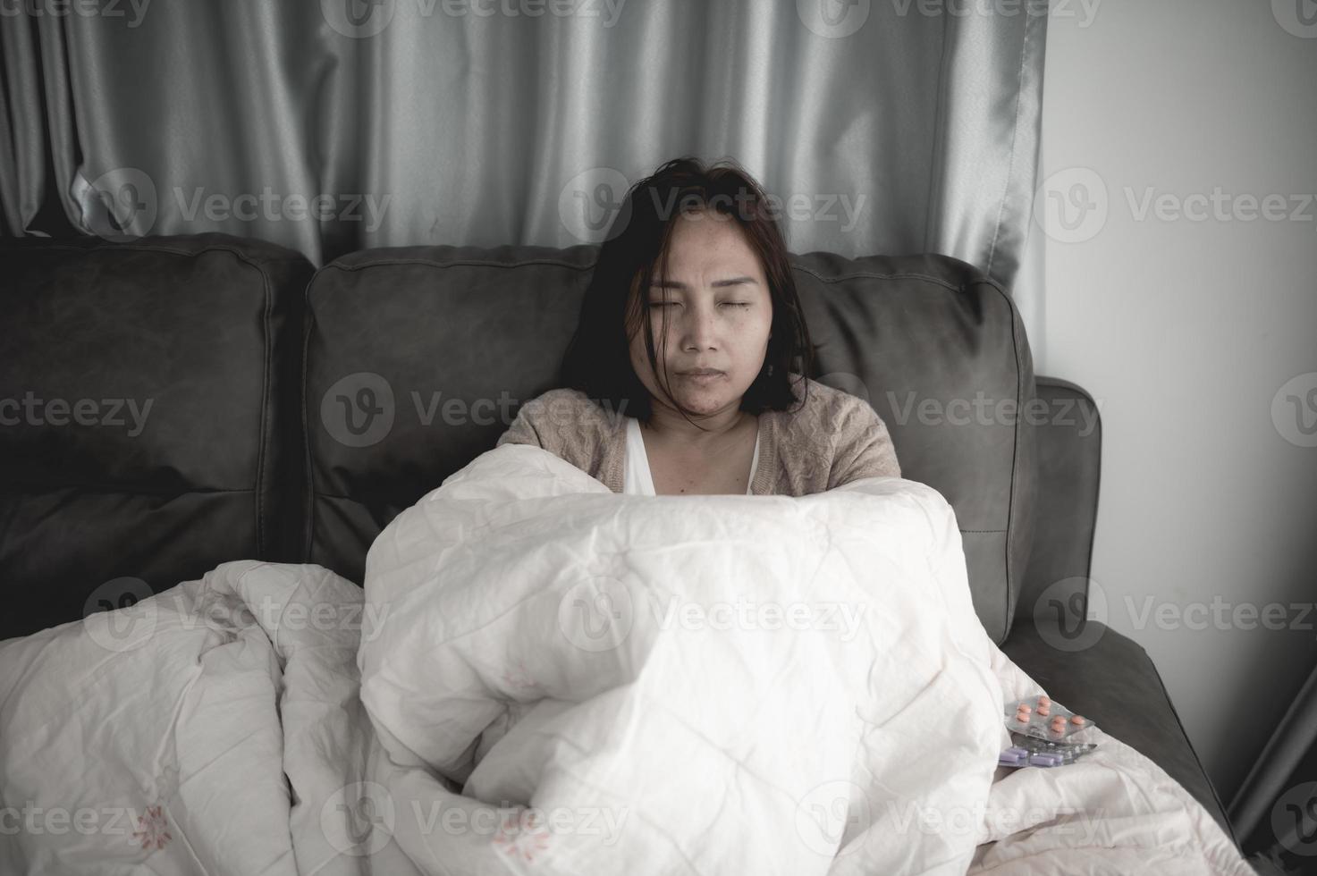 une femme malade asiatique s'assoit sur le canapé reste à la maison, la femme se sentait mal, voulait s'allonger et se reposer, forte fièvre photo