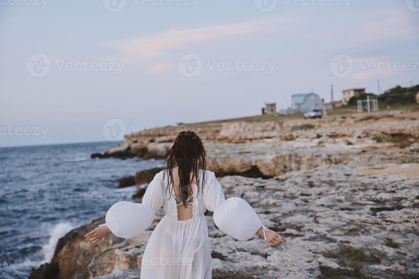 femme dans blanc robe des promenades sur le plage des pierres retour vue photo