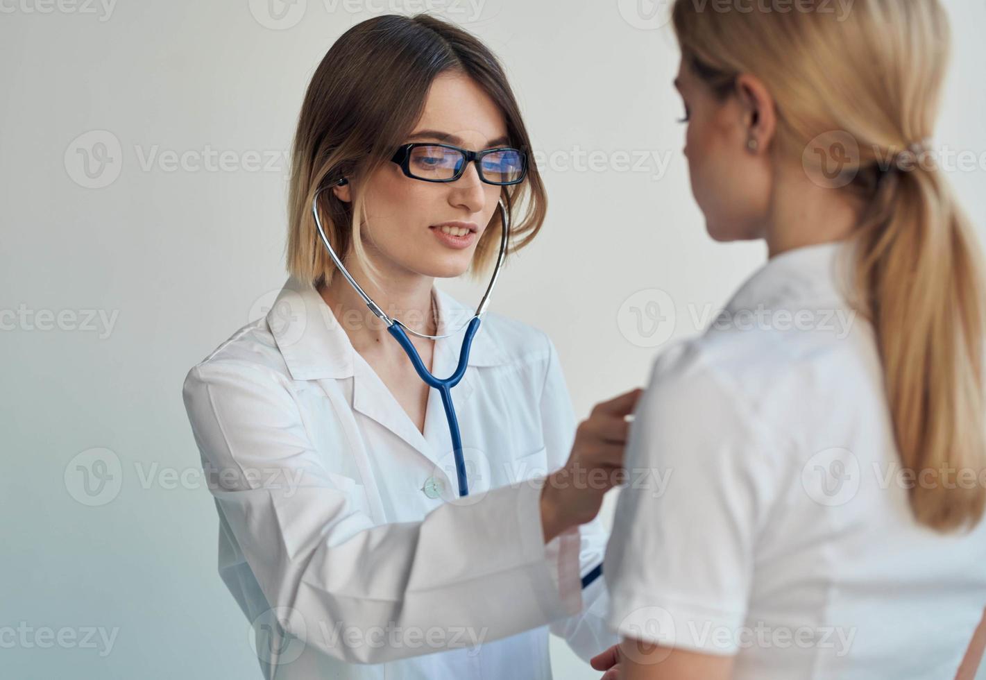 retour vue de content femme médecin avec stéthoscope et femelle patient à l'intérieur photo