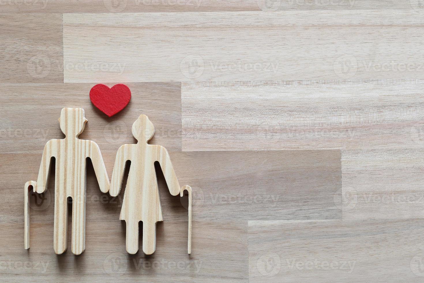 Découpe en bois d'un couple et en forme de coeur sur fond de bois photo