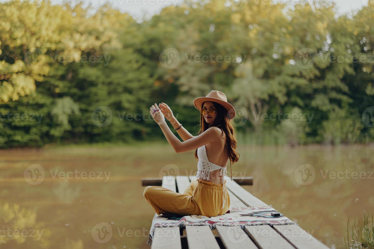 une femme yogi est assis avec sa retour à le berge de rivière sur une pont et médite sur relaxant sa corps dans la nature photo