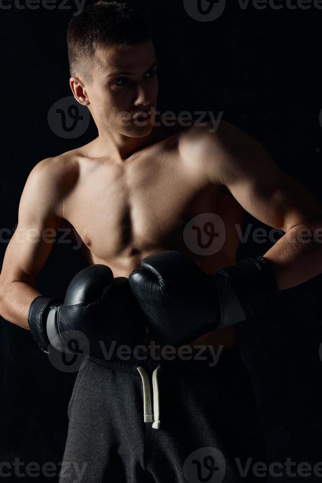 Masculin athlète boxe gants sur noir Contexte faire des exercices photo