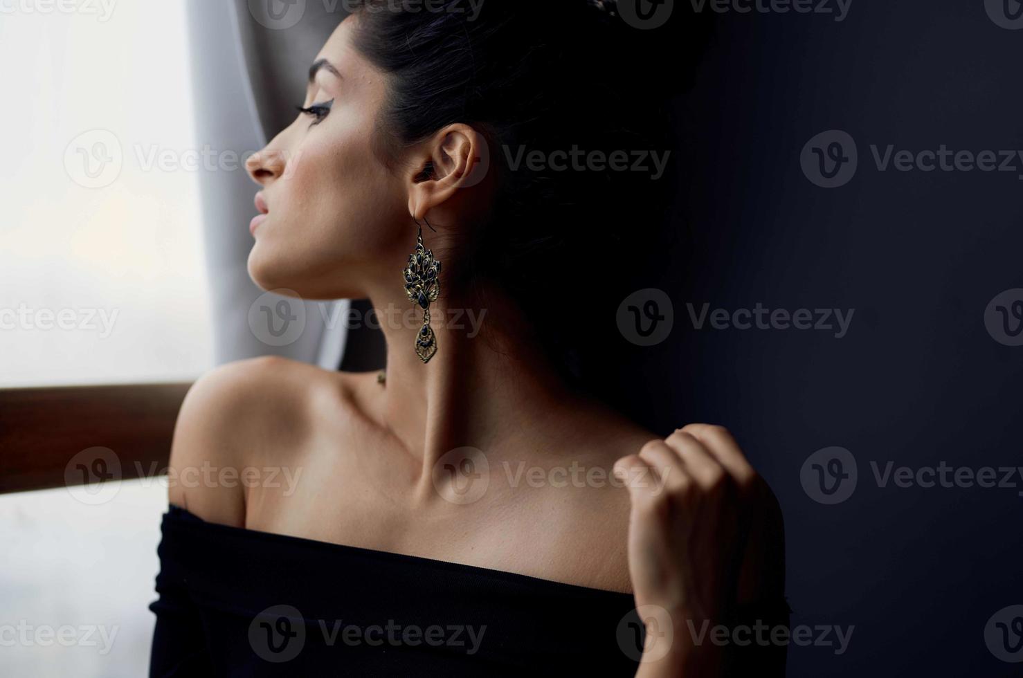 jolie femme près fenêtre posant attrayant Regardez des boucles d'oreilles élégant style photo
