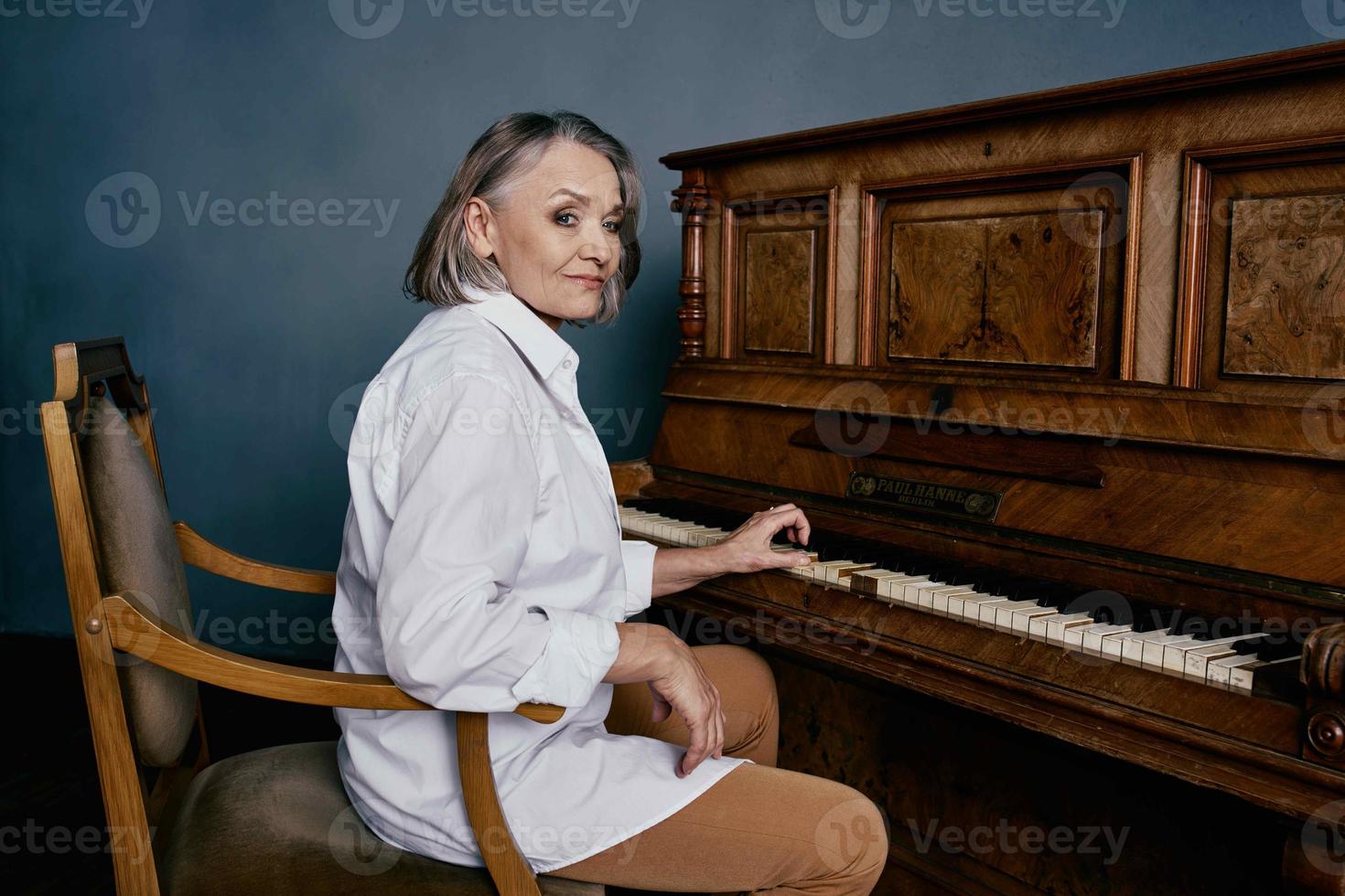 personnes âgées femme séance sur une chaise près le piano la musique performance photo