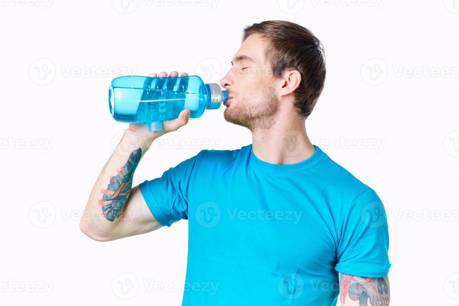 gars athlète les boissons l'eau de une bouteille sur une blanc Contexte et une bleu T-shirt photo