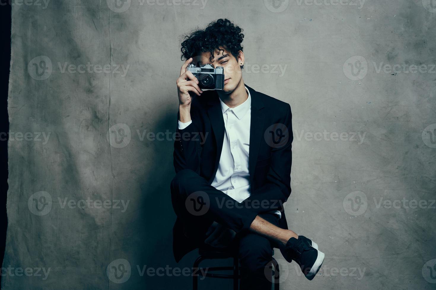 gars dans une classique costume à l'intérieur avec une caméra dans main et baskets brunet loisir photo