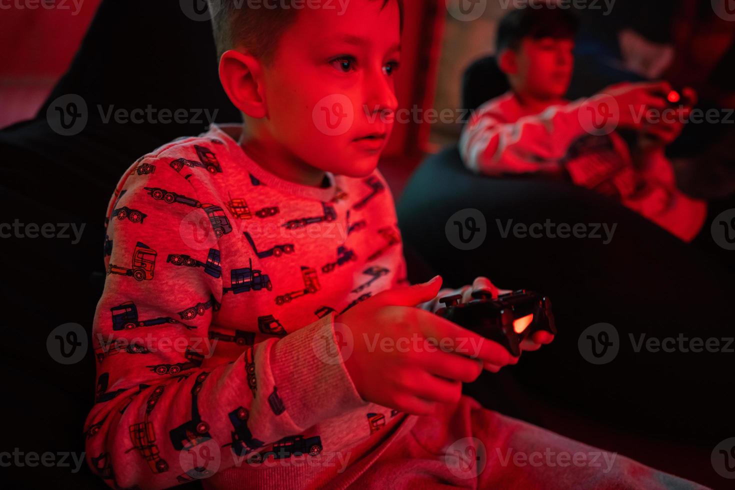 deux garçons les joueurs jouer manette de jeu vidéo Jeu console dans rouge jeu chambre. photo