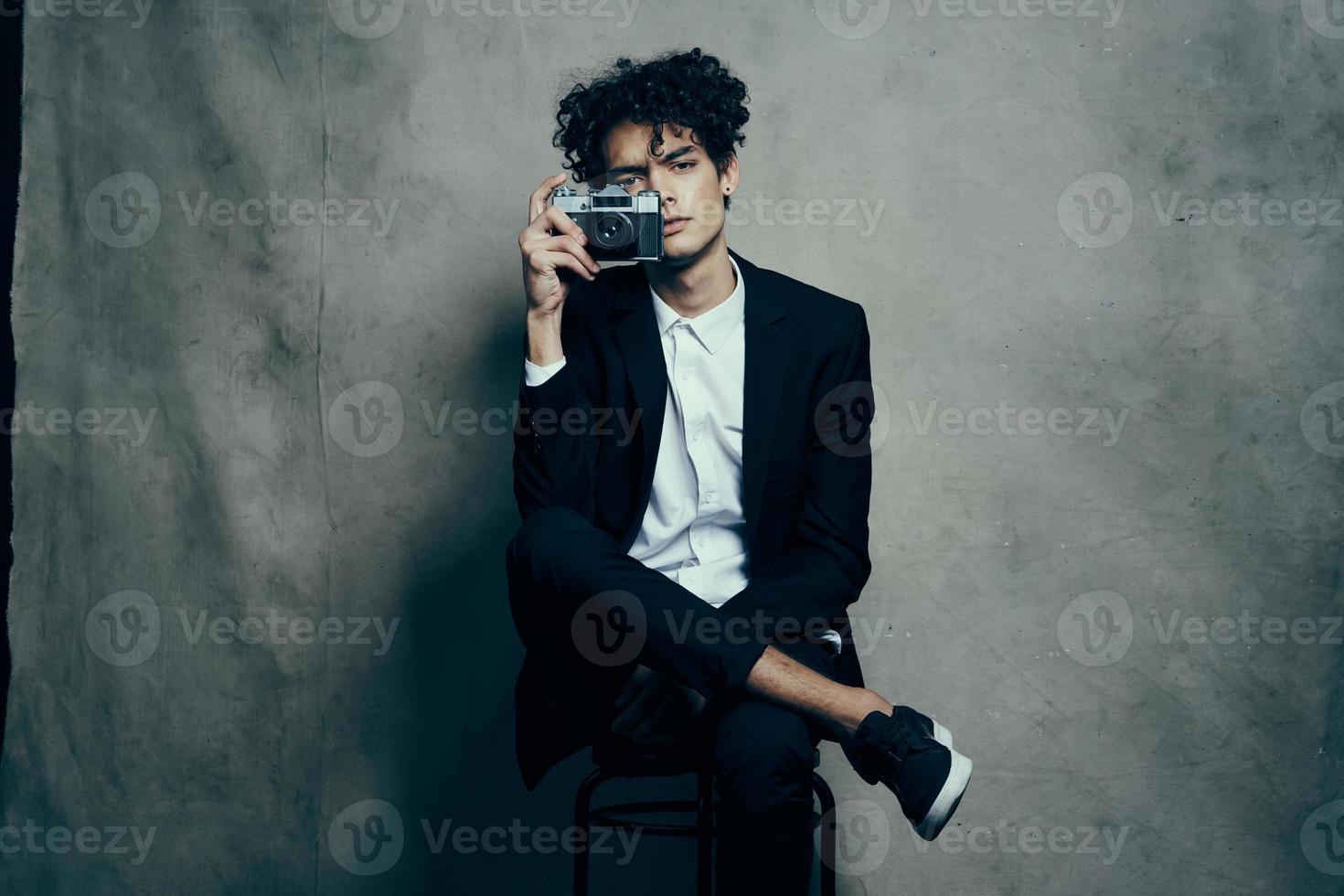 gars dans une classique costume à l'intérieur avec une caméra dans main et baskets brunet loisir photo