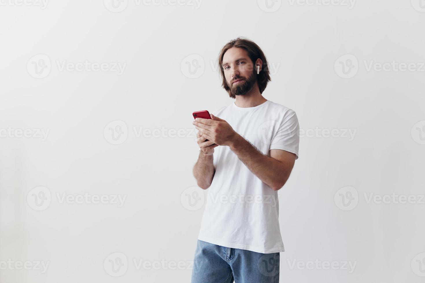 homme blogueur détient une téléphone dans le sien mains et communique avec gens en ligne dans social réseaux avec une sourire et une blanc T-shirt sur une blanc Contexte photo