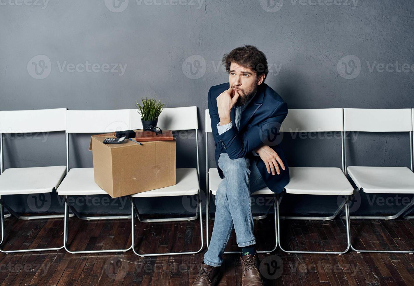 une homme avec des choses dans une boîte est assis sur une chaise attendre pour mécontentement photo