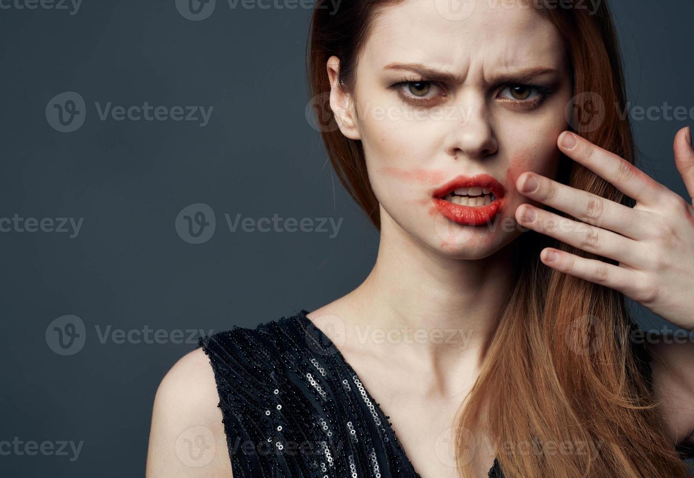 femme dans noir robe émouvant visage avec mains et rouge à lèvres stress irritabilité photo