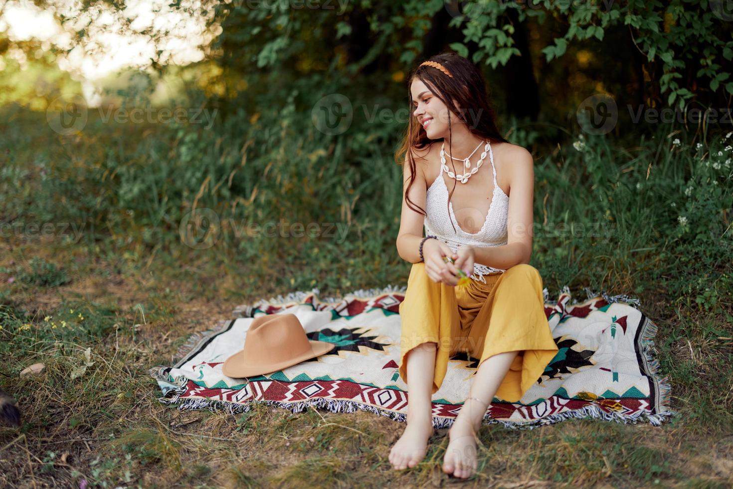 fille habillé comme une hippie éco relaxant dans le parc, séance sur une couverture dans le coucher de soleil, détendu mode de vie photo