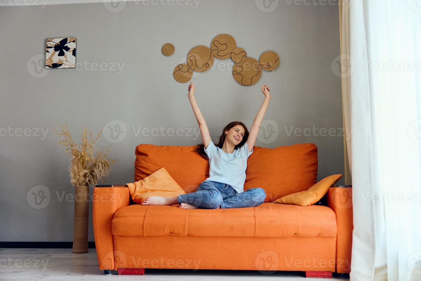 souriant femme relaxant à Accueil dans le pièce sur le canapé intérieur inchangé photo