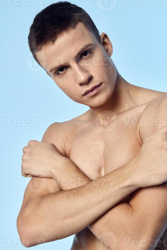 sportif homme en portant le sien épaules pompé en haut torse bodybuilder Regardez tout droit bleu Contexte photo