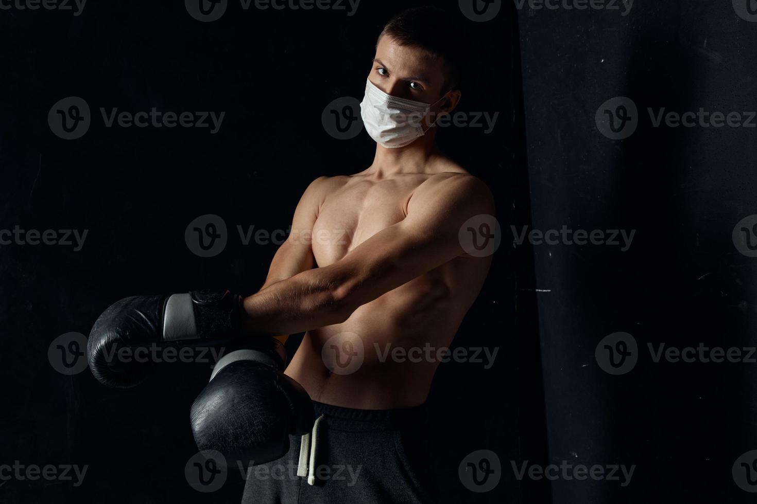 portrait de une boxeur dans une médical masque et noir gants sur un isolé Contexte photo