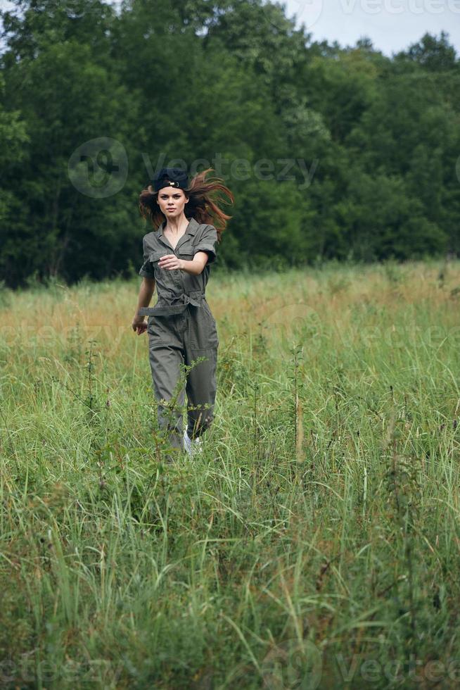 femme dans le Prairie fonctionnement sur grand herbe dans vert combinaison photo