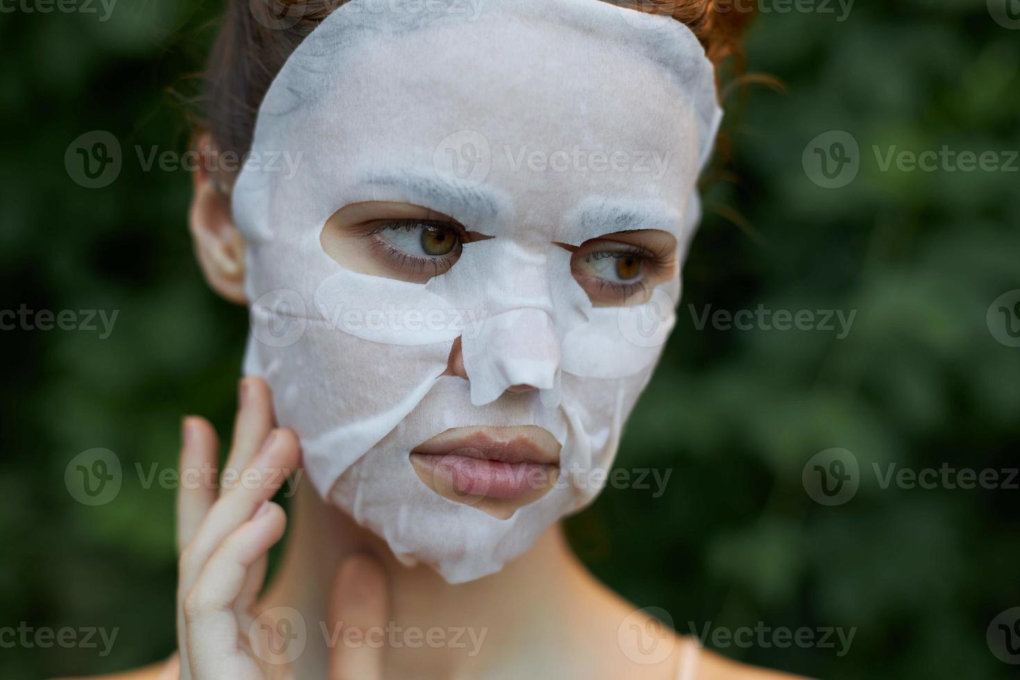 agréable femme cosmétique masque regards à le côté et touche une doigt près le visage nu épaules photo