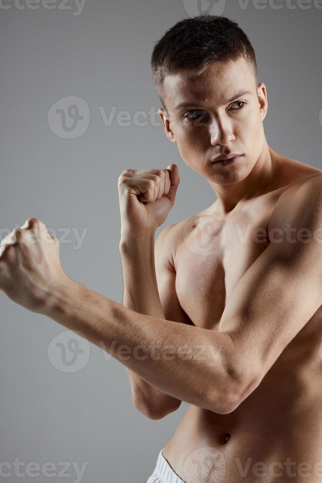 Beau sportif avec nu torse sur gris Contexte et biceps bodybuilder photo