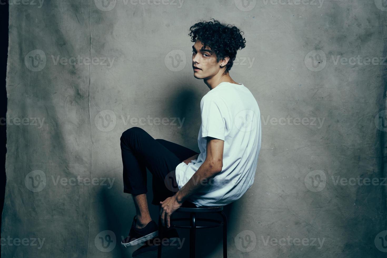 glamour adolescent dans un pantalon et T-shirt frisé cheveux en tissu toile de fond photocall studio photo