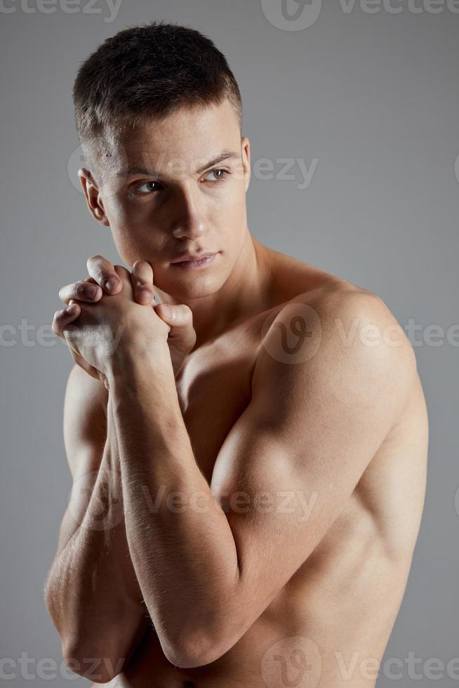 portrait de une gars sur une gris Contexte nu bras muscles bodybuilder aptitude photo