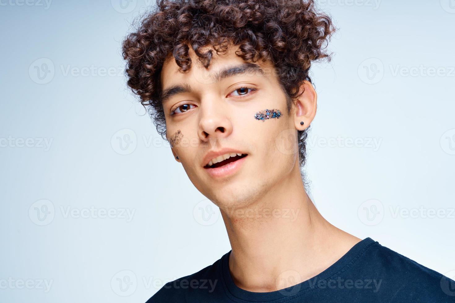 gars avec frisé cheveux s'applique une noir masque sur le sien visage cosmétologie photo