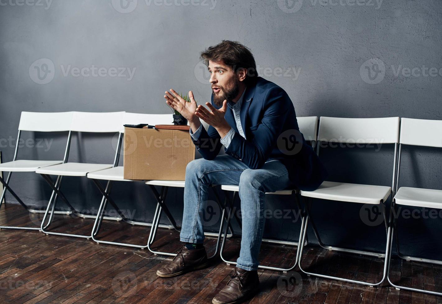 une homme dans une costume est assis sur une chaise avec une boîte emploi chercher la dépression photo