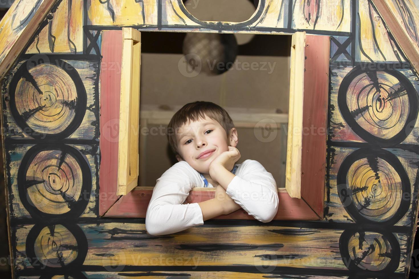 mignonne garçon Regardez en dehors le fenêtre de le jouet maison. photo