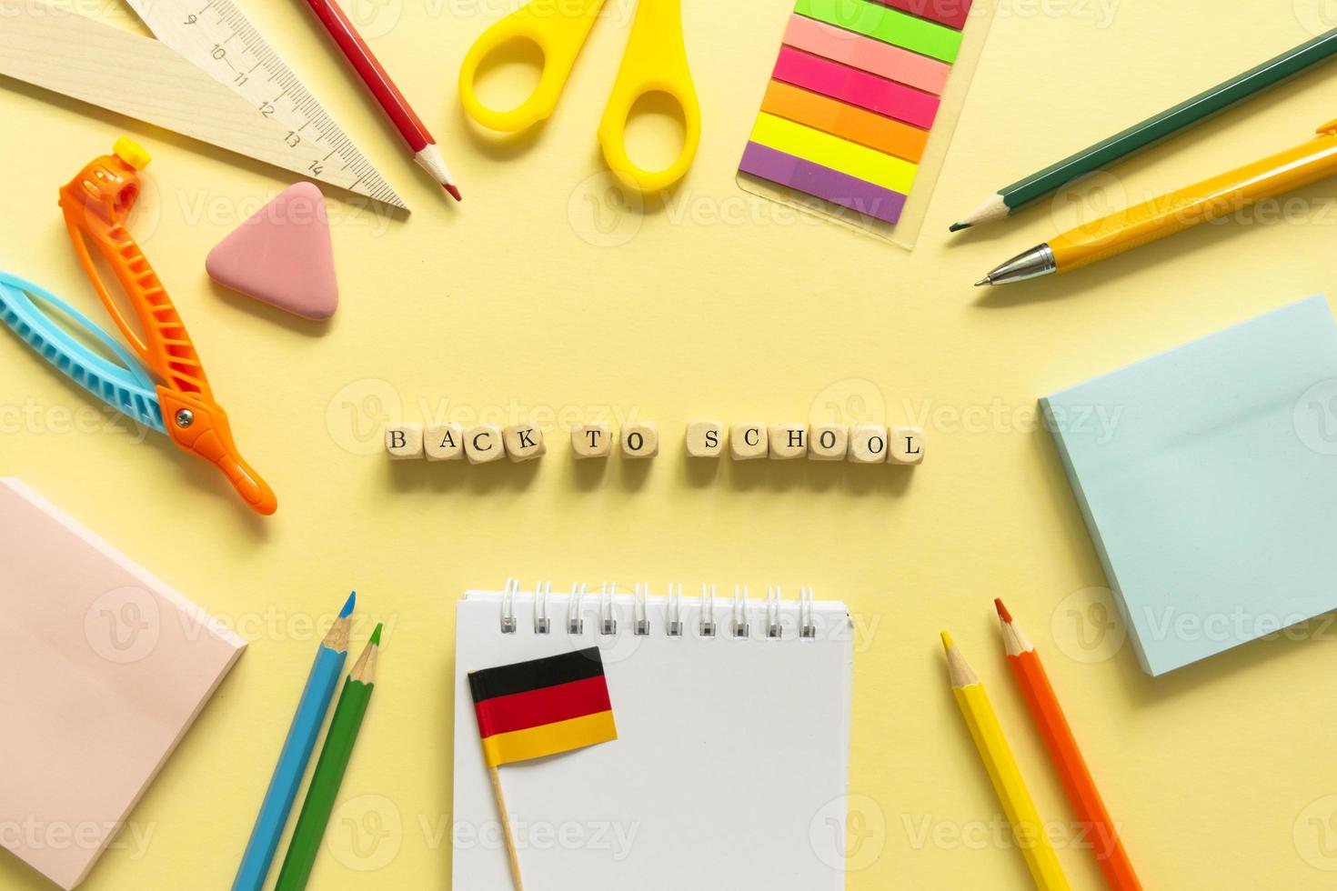 retour à l'école. accessoires scolaires sur fond jaune. blocs de bois avec des lettres photo