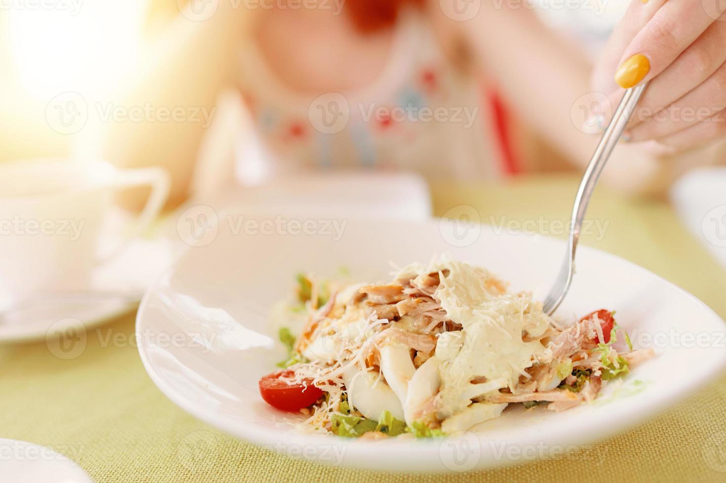 La main de la femme tient une fourchette dans une assiette de salade photo