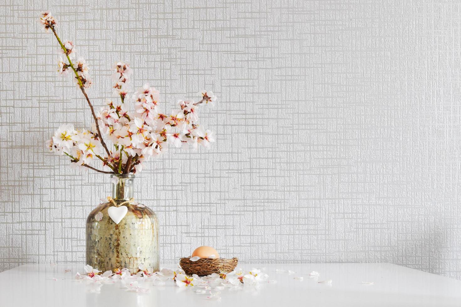 Vase avec des marguerites blanches colorées fraîches dans un vase, décoration d'oeufs de Pâques sur table blanche photo