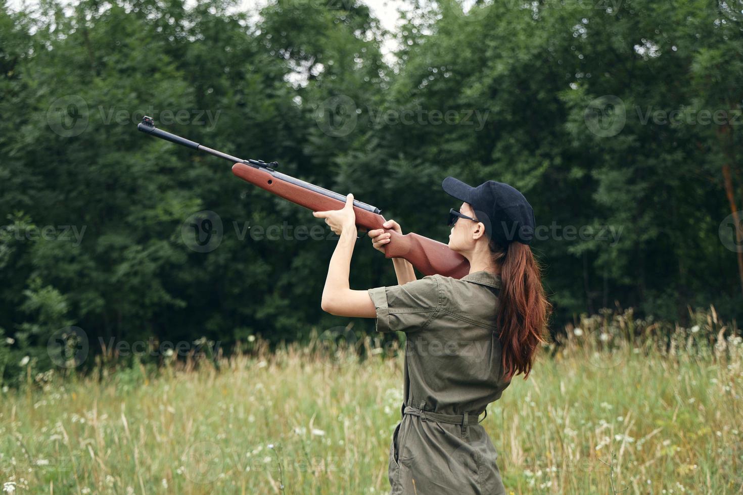 femme sur la nature avec une fusil Frais air Voyage chasse vert salopette photo