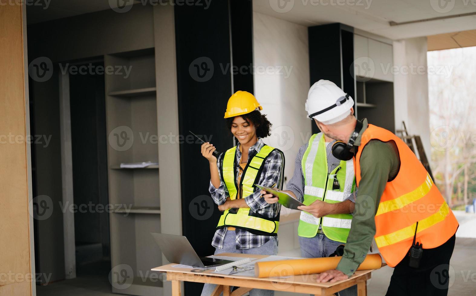 architecte caucasien homme et femme travail avec collègues mixte course dans le construction placer. architecture ingénierie sur gros projet. bâtiment dans construction processus intérieur. photo