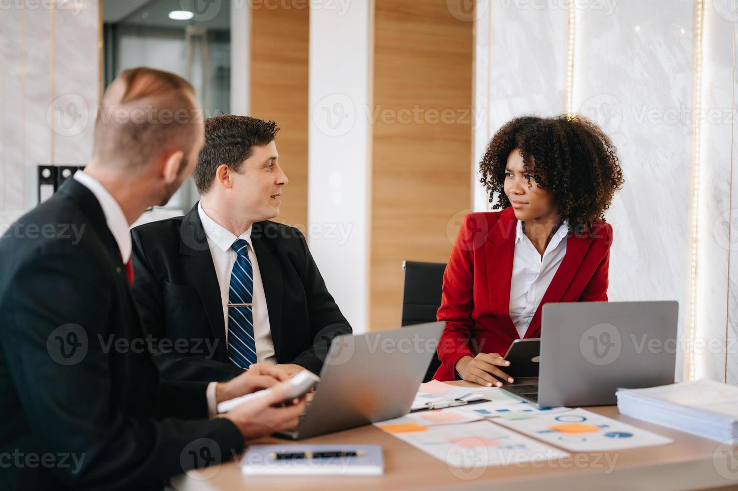 des hommes d'affaires heureux tout en collaborant sur un nouveau projet dans un bureau. groupe d'hommes d'affaires divers utilisant un ordinateur portable et une tablette au bureau. photo