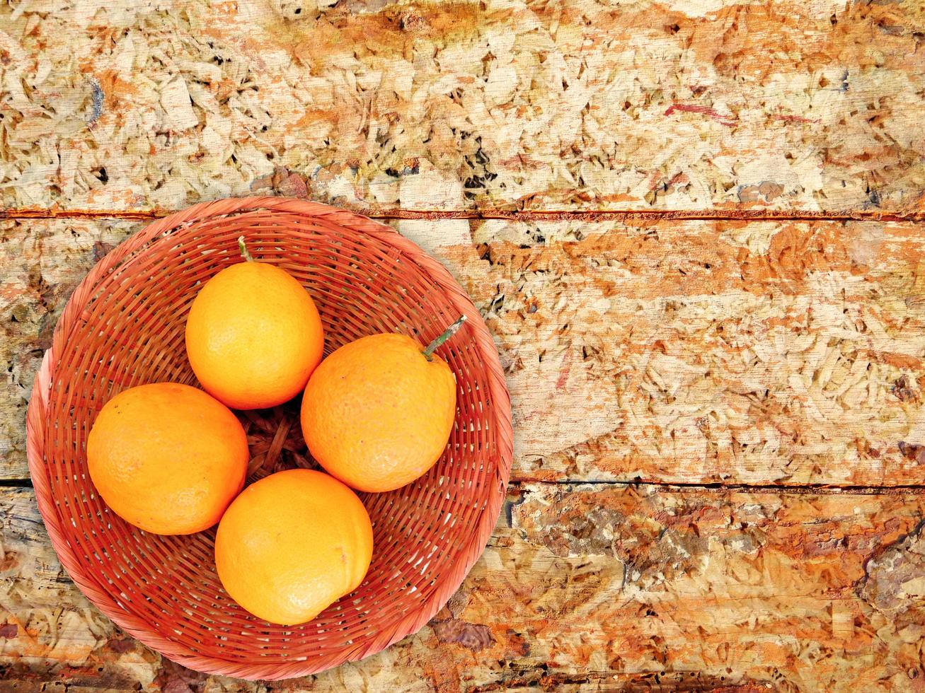 Oranges dans un bol en osier sur un fond de table en bois photo