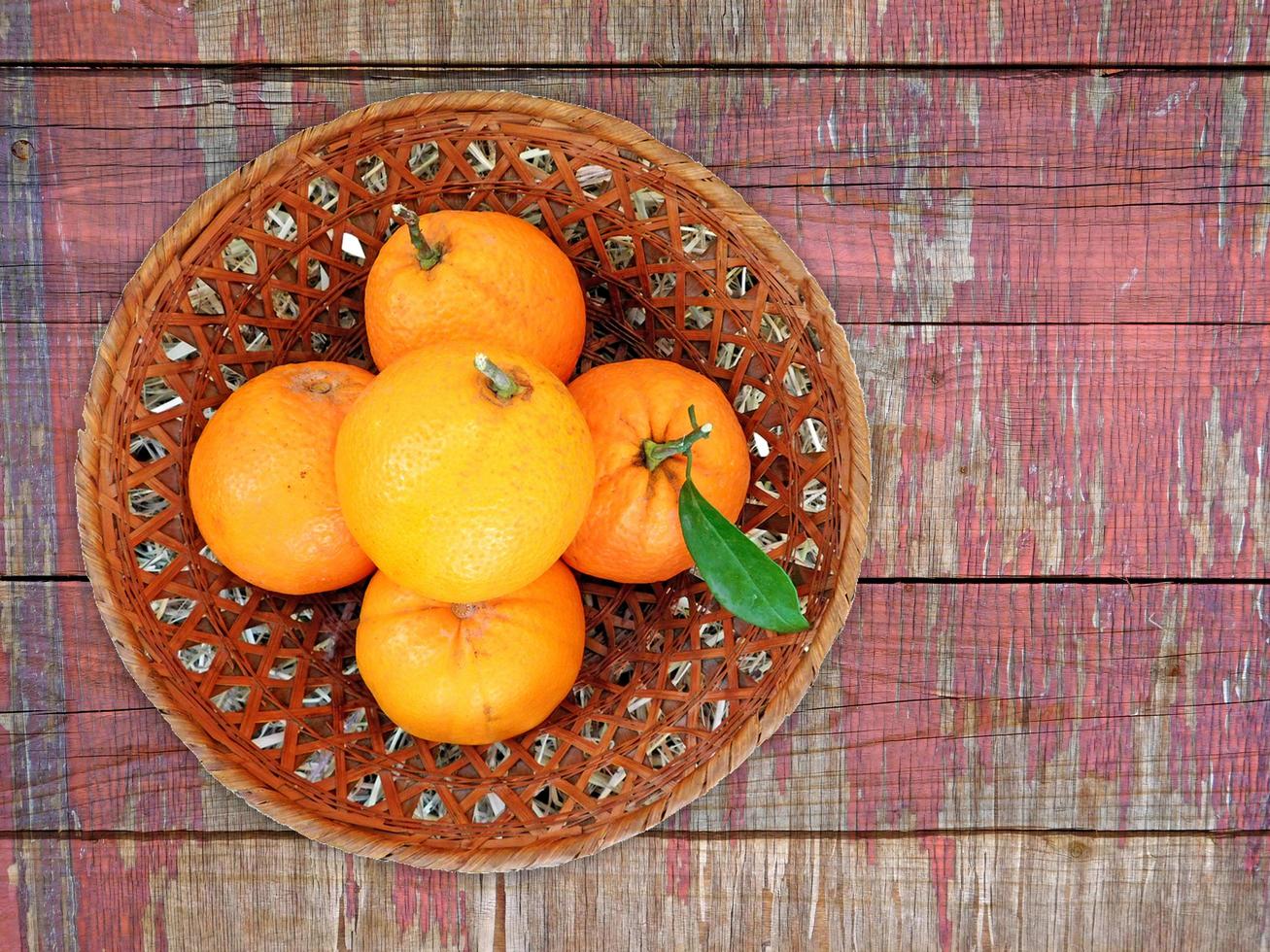 Oranges dans un bol en osier sur un fond de table en bois photo
