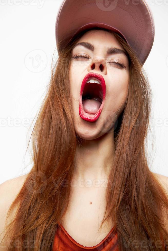 femme dans une casquette ouvre le sien bouche large avec amusement émotions fermé yeux Orange robe photo