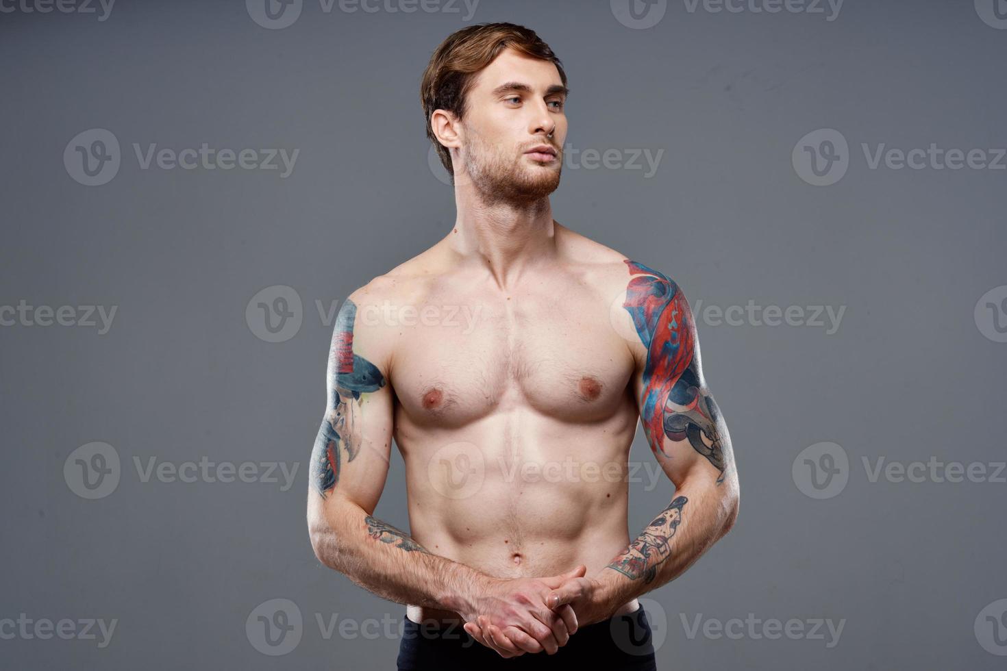 sportif homme avec tatouages sur le sien bras pompé en haut presse macho gris Contexte photo