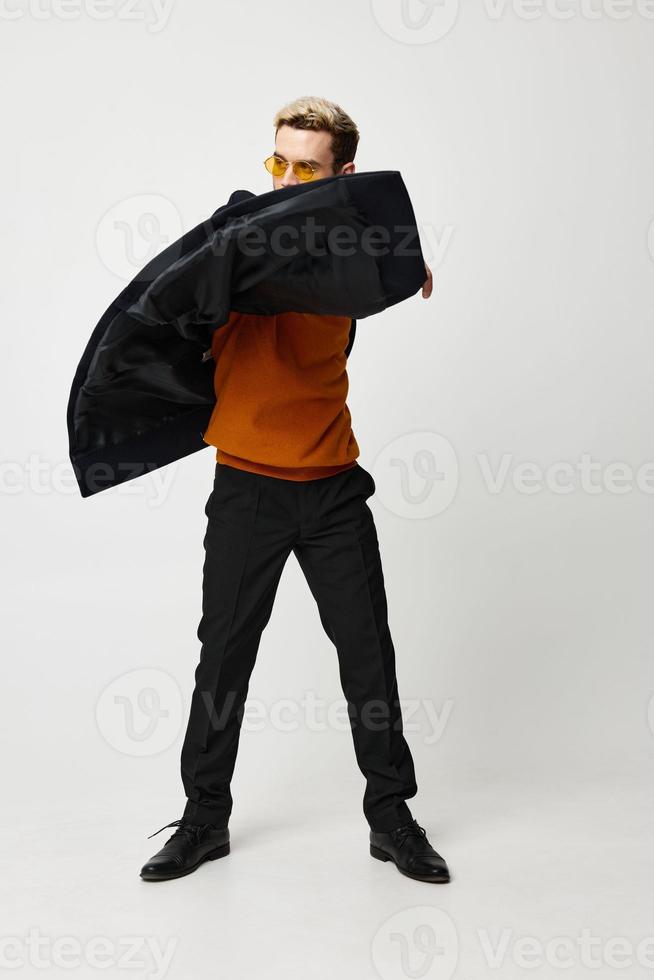 agréable gars dans pantalon et un Orange chandail foncé manteau modèle lumière Contexte photo
