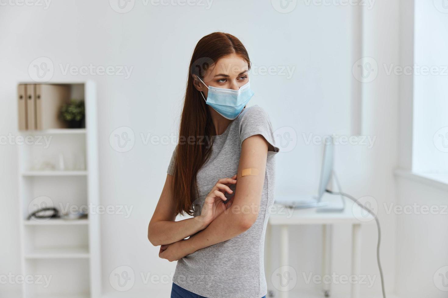 femme dans hôpital médical masque avec germicide plâtre sur épaule à la recherche en dehors le fenêtre convoitise passeport photo
