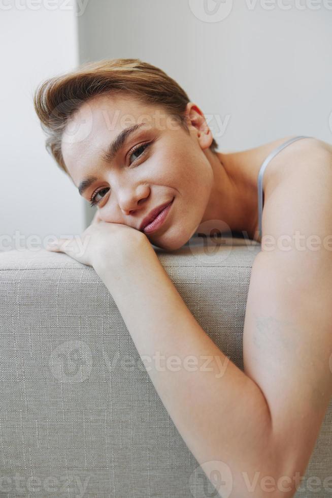 content femme sourire mensonge à Accueil sur le canapé relaxant sur une fin de semaine à Accueil avec une court la Coupe de cheveux cheveux sans pour autant filtres sur une blanc arrière-plan, gratuit copie espace photo