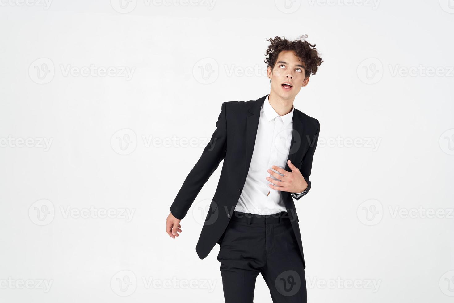 Jeune gars dans une classique costume sur une lumière Contexte frisé cheveux portrait tondu vue photo