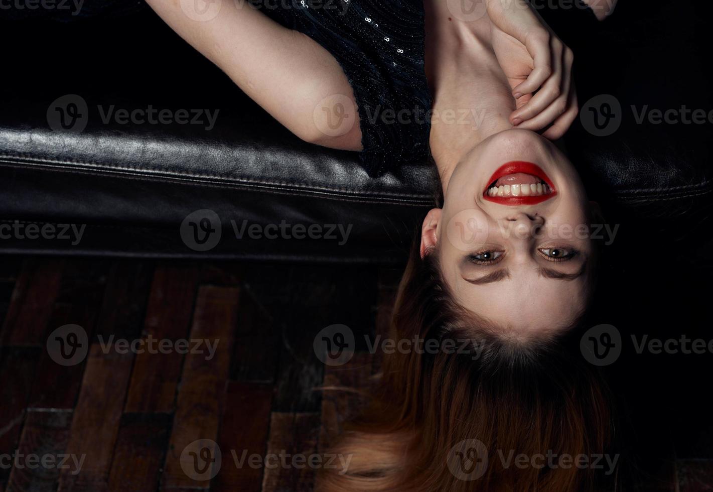 magnifique femme avec brillant maquillage mensonges sur une cuir canapé fermer rouge cheveux modèle photo