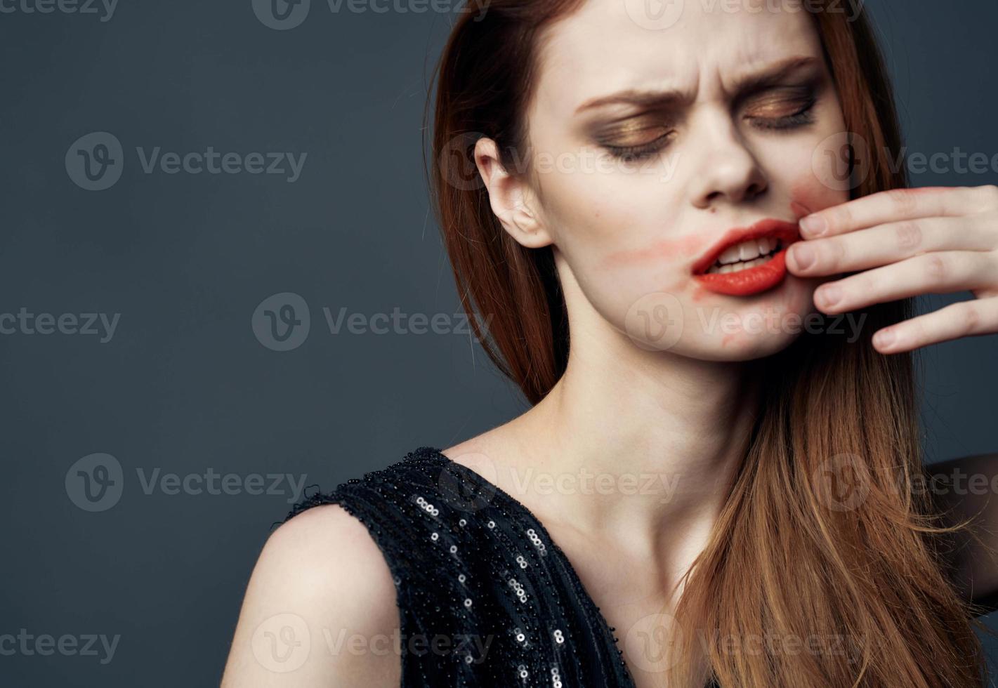 femme dans noir robe émouvant visage avec mains et rouge à lèvres stress irritabilité photo