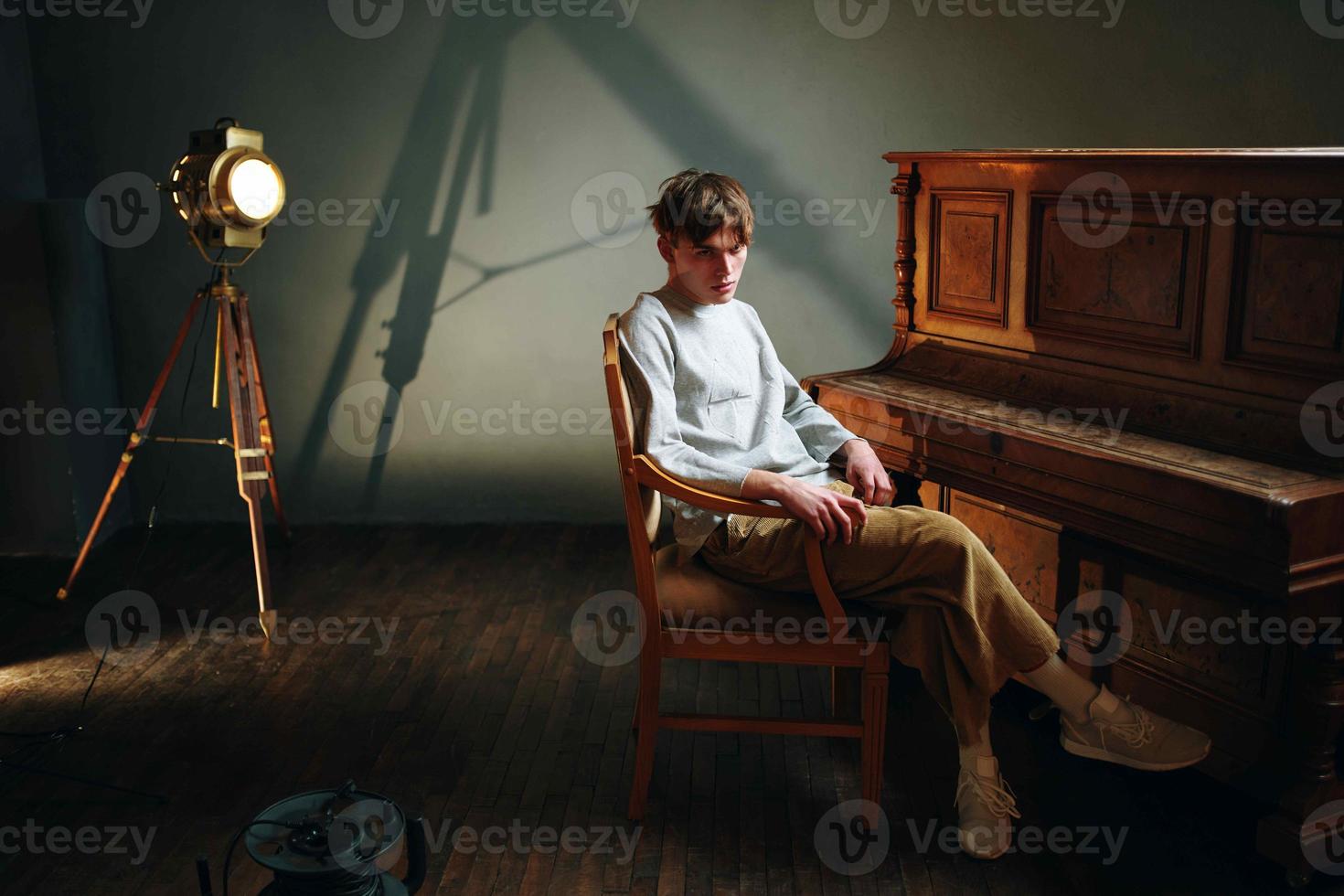 gars séance près le piano posant studio projecteur photo