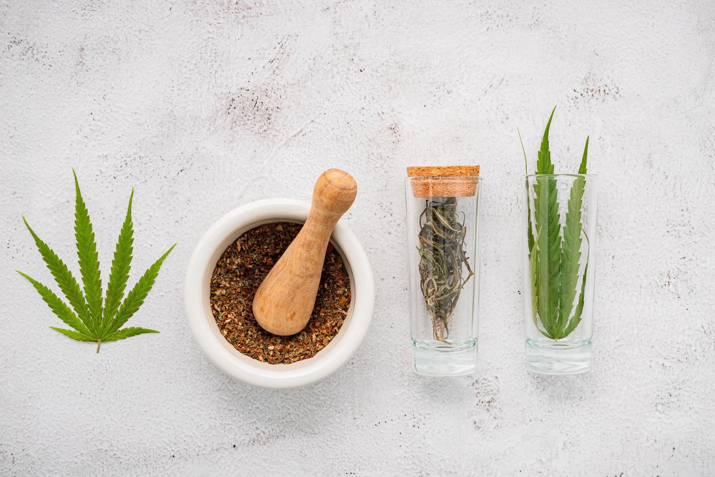 Bouteille en verre d'huile de chanvre avec un mortier blanc et des feuilles de chanvre mis en place sur un fond de béton, concept d'aromathérapie photo