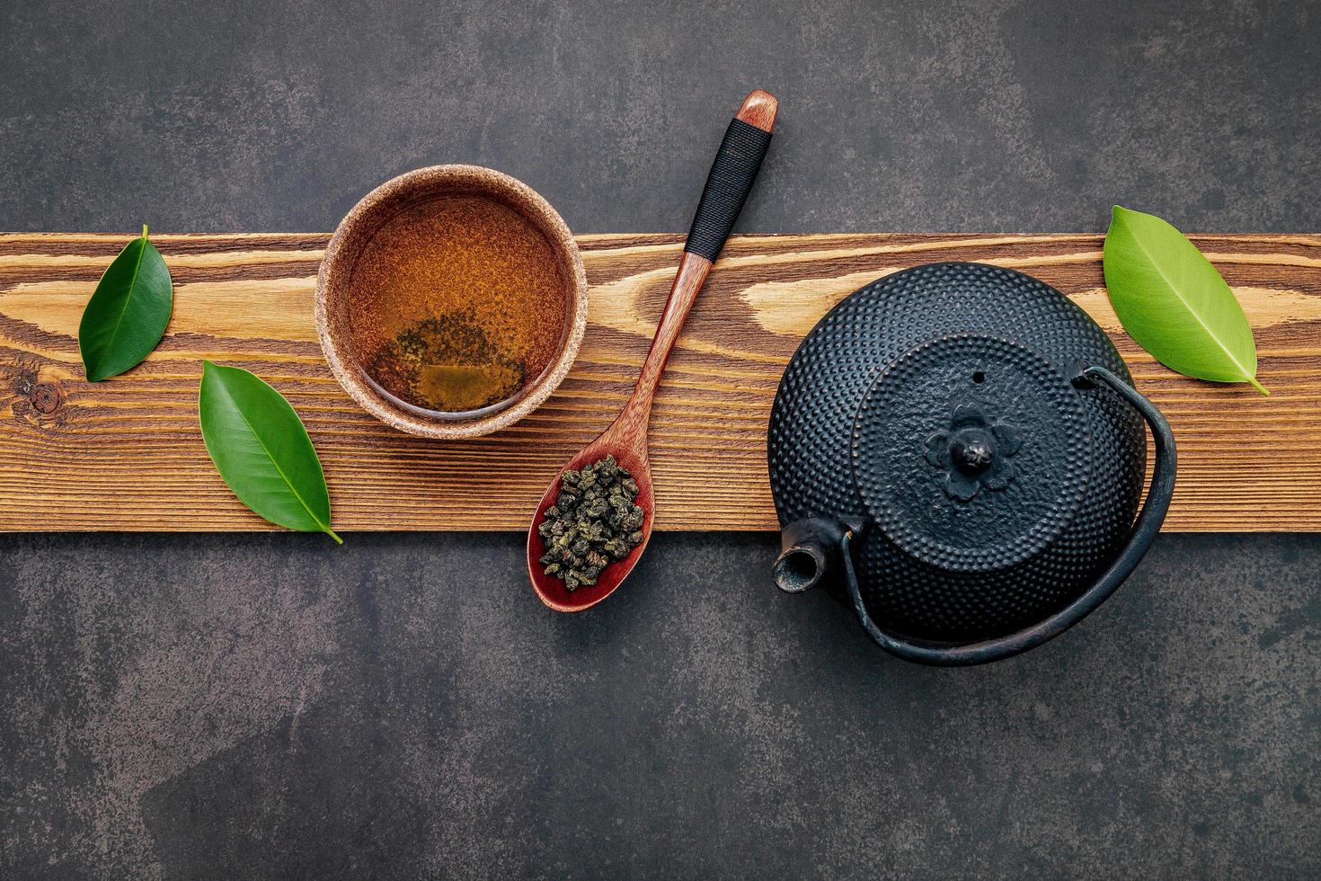 Théière en fonte noire avec tisane mis en place sur un fond de pierre sombre photo