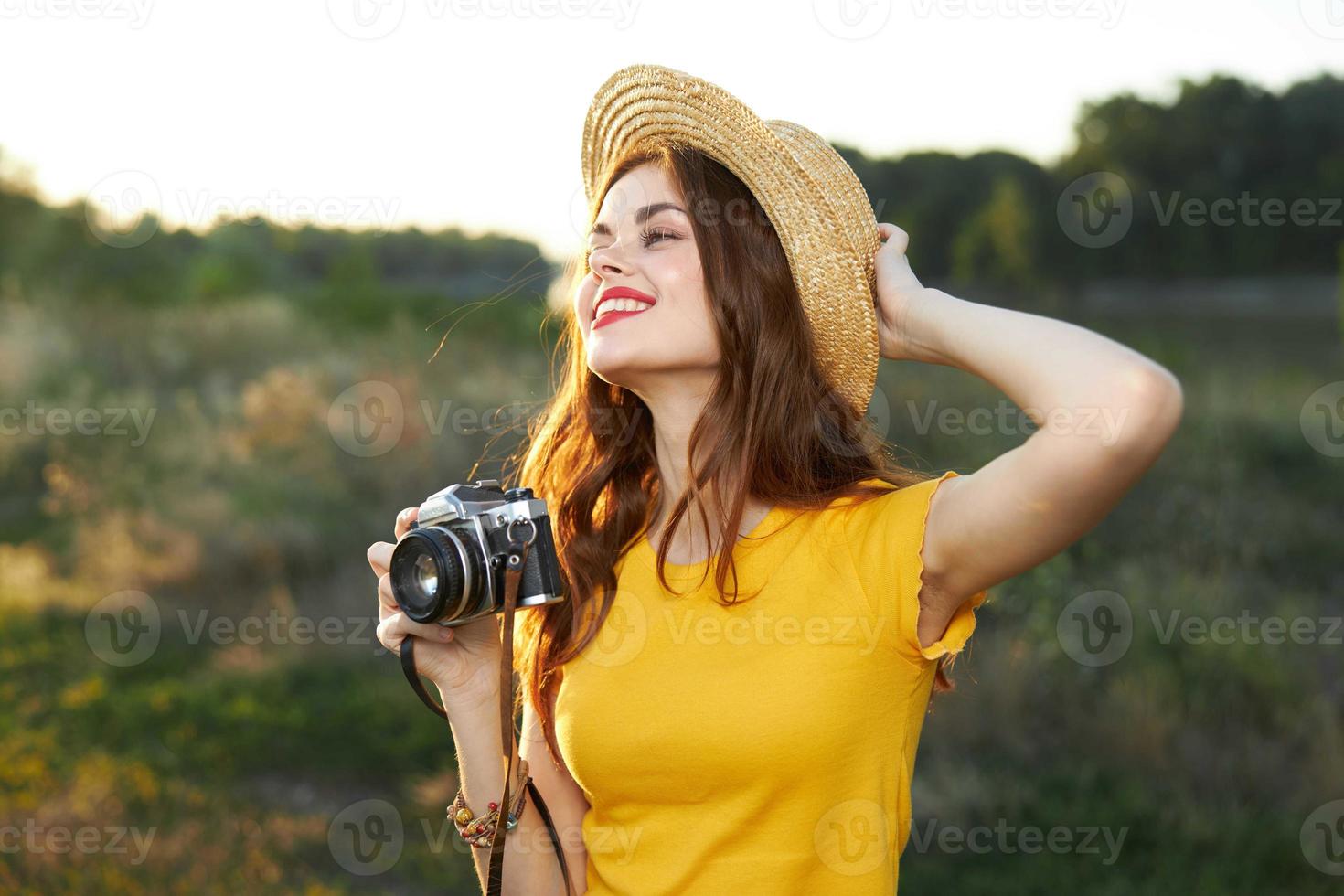 souriant femme en portant main sur chapeau caméra la nature Frais air photo