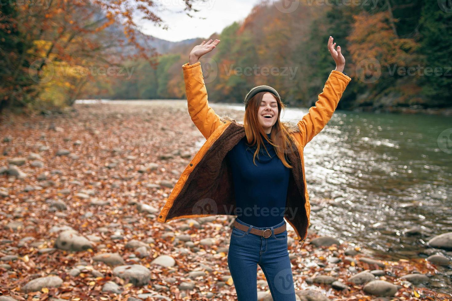 de bonne humeur femme dans une Jaune veste près le rivière l'automne marcher photo